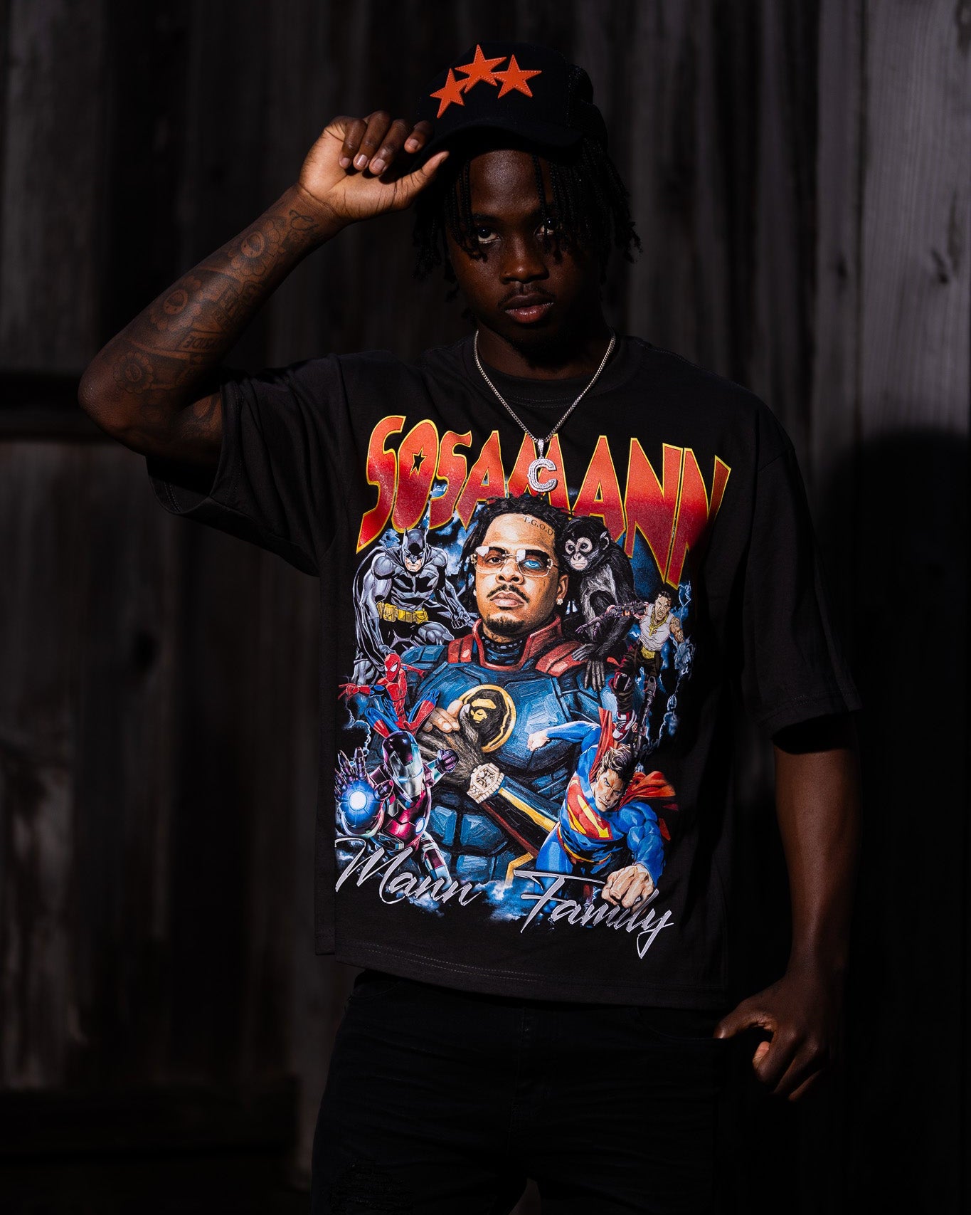 Person wearing a superhero graphic t-shirt with colorful design and text, standing against a dark background.