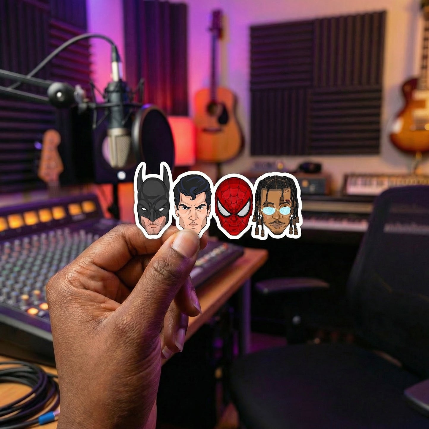 Hand holding stickers of superhero characters in a music studio setting
