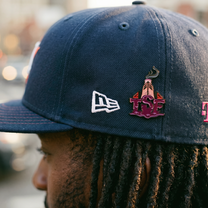Person wearing a blue cap with TSF pins, blurred background Sosamann sauce walka fitted cap accessories 