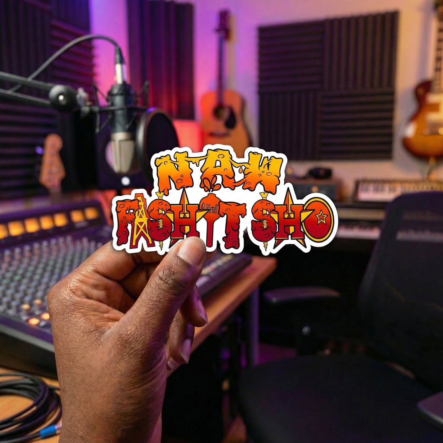 Hand holding a naw fashitsho sticker with text in a music studio