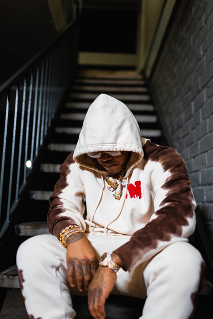 sosamnn wearing a brown and white hoodie sitting on a staircase.