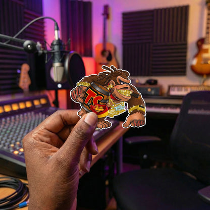 Hand holding a sticker of a saucy kong character in a recording studio